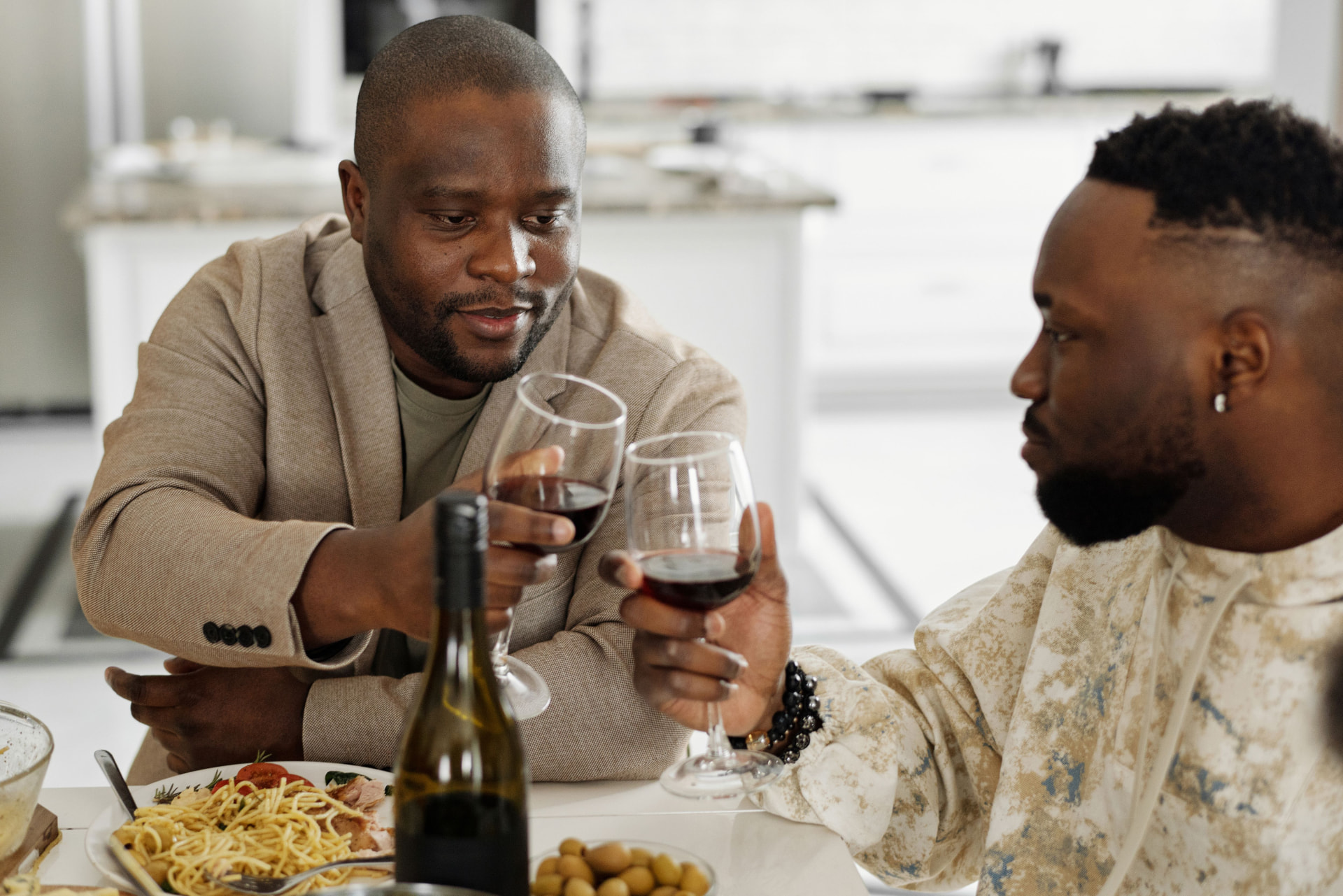 Two dads sharing a meal and toasting with wine glasses